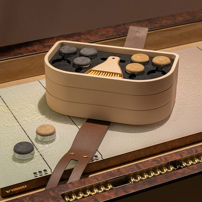 Close‑up of Vismara Flume shuffleboard playing pieces and brush set in organised tray on tabletop with glossy wood trim – sophisticated gaming accessories.