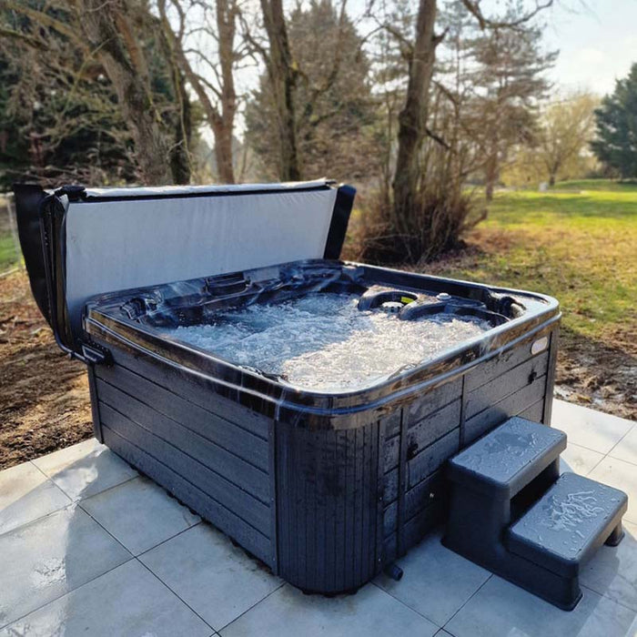 Side view of Wellis Valencia Hot Tub in use outdoors, bubbling water and natural setting highlight premium hot tub experience.