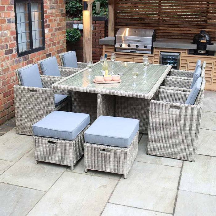 Wentworth 10 Seater Cube Dining Set arranged in a garden patio, featuring comfortable grey cushions and a glass-topped table for outdoor dining.