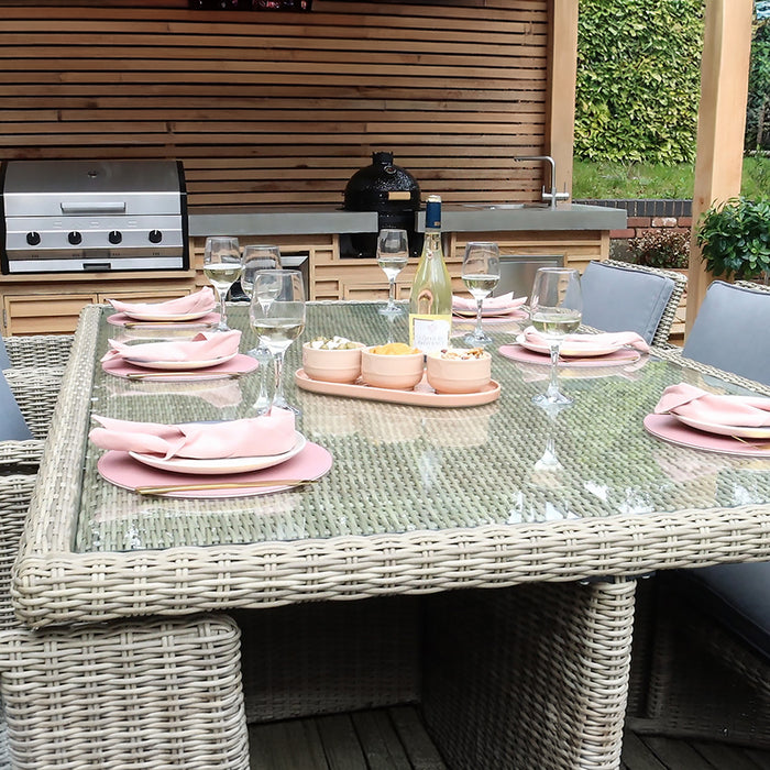 Wentworth 10 Seater Cube Dining Set with a glass-topped table, set for dining under a pergola in an outdoor kitchen, perfect for garden gatherings.