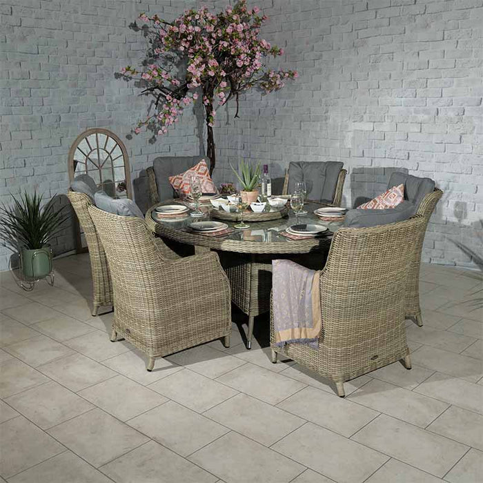 A beautifully arranged indoor scene featuring the Wentworth 6 Seater Ellipse Imperial Dining Set, complete with rattan chairs and a glass-top oval table.