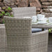 A side angle capturing the detailed wicker design of the chairs in the Wentworth 6 Seater Round Carver Dining Set, set against a natural stone background.