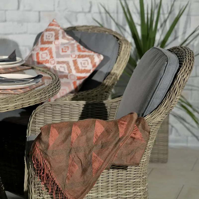 Detail of a cushioned rattan chair from the Wentworth 6 Seater Round Imperial Dining Set, with an orange patterned cushion adding a pop of colour.