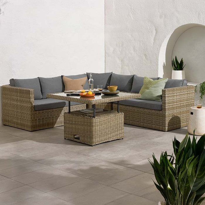 The Wentworth Adjustable Corner Lounge Set styled in an outdoor setting, featuring a modular sofa and adjustable table with grey cushions.