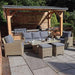 Outdoor lifestyle image of the Wentworth Deluxe Sofa Dining Set, featuring grey cushions and a sturdy glass-top dining table setup.