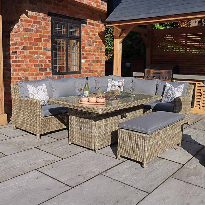 Wentworth Fire Pit Corner Lounge Set with Rectangular Table at night, featuring warm fire pit lighting and inviting outdoor seating.