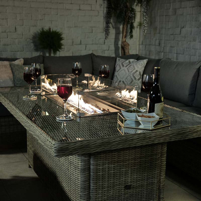 Close-up of the Wentworth Fire Pit Dining & Lounge Set at night, showing the fire pit table with surrounding glass panels.