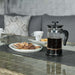 Close-up view of a coffee setup with cookies on the Wentworth fire pit table, showing the dining area's utility.