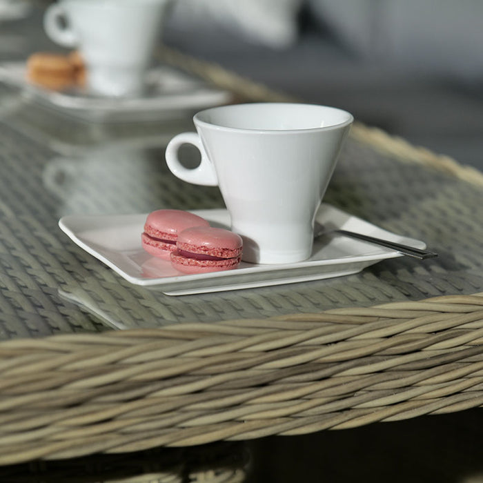 A close-up of macaroons and a coffee cup placed on the glass-top table of the Wentworth Fire Pit Corner Dining & Lounge Set.