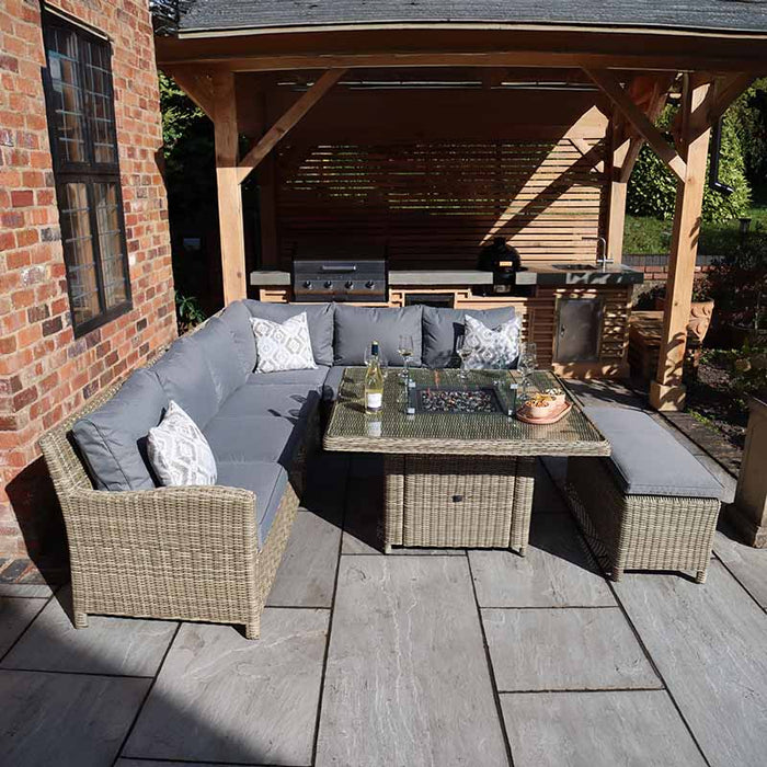 Wentworth Fire Pit Dining & Lounge Set with Square Table featuring comfortable grey cushions in a charming backyard setting, perfect for outdoor gatherings.