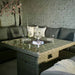 Wentworth Fire Pit Dining & Lounge Set with square table, beautifully lit for a serene evening gathering with friends.