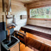 Woodnest Alice outdoor sauna interior with tiered timber benches, panoramic window and Harvia wood-burning sauna heater.