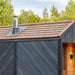 Woodnest Alice 2-3 Person Outdoor Sauna roof detail with natural wood shingles, metal chimney and dark timber cladding.