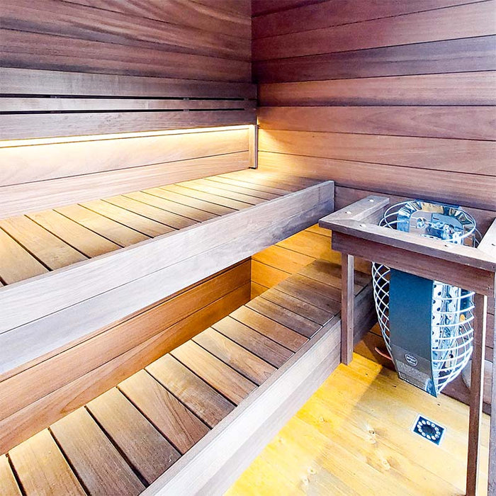 Woodnest Lucia outdoor sauna interior featuring tiered timber benches, ambient lighting and an electric sauna heater with protective guard.