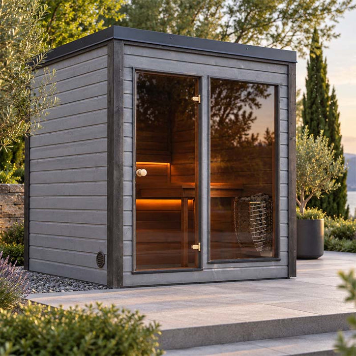 Woodnest Lucia 2 Person Outdoor Sauna with grey timber cladding, full-height glass front and warmly lit interior in a landscaped garden.