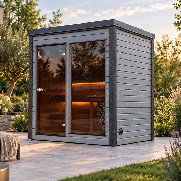 Woodnest Lucia 2 Person Outdoor Sauna featuring a modern grey timber exterior, glass entrance and illuminated wooden benches in a garden setting.