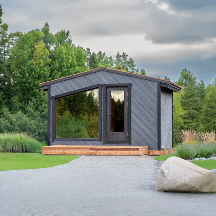 Woodnest Maria 2-4 Person Outdoor Sauna in a landscaped garden with grey timber exterior, panoramic window and glass door.