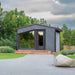 Woodnest Maria 2-4 Person Outdoor Sauna in a landscaped garden with grey timber exterior, panoramic window and glass door.