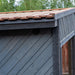 Woodnest Maria outdoor sauna roof detail showing grey timber cladding, dark trim, ventilation and natural wood roofing.