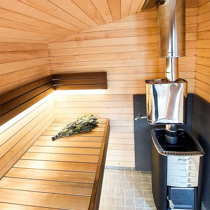 Woodnest Maria 2-4 Person Outdoor Sauna interior featuring timber benches, ambient lighting and a wood-burning sauna heater.