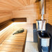 Woodnest Maria 2-4 Person Outdoor Sauna interior featuring timber benches, ambient lighting and a wood-burning sauna heater.