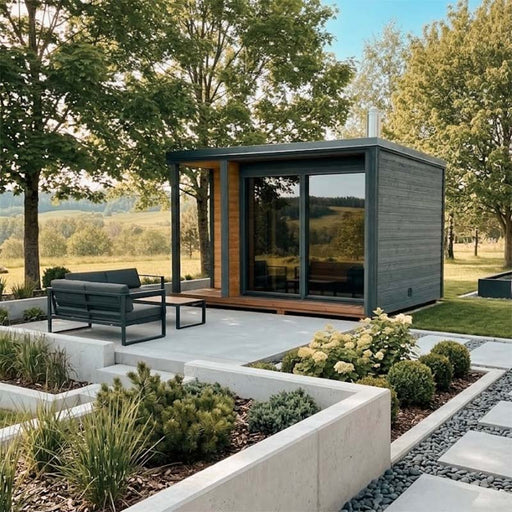 Woodnest Nora 3-4 Person Outdoor Sauna with grey timber cladding, covered terrace and large glazed entrance in a landscaped garden.