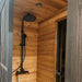Woodnest Nora 3-4 Person Outdoor Sauna shower area featuring natural timber walls and a modern black rainfall shower.