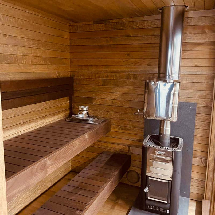Woodnest Nora 3-4 Person Outdoor Sauna interior with tiered timber benches and Harvia wood-burning sauna heater with chimney.